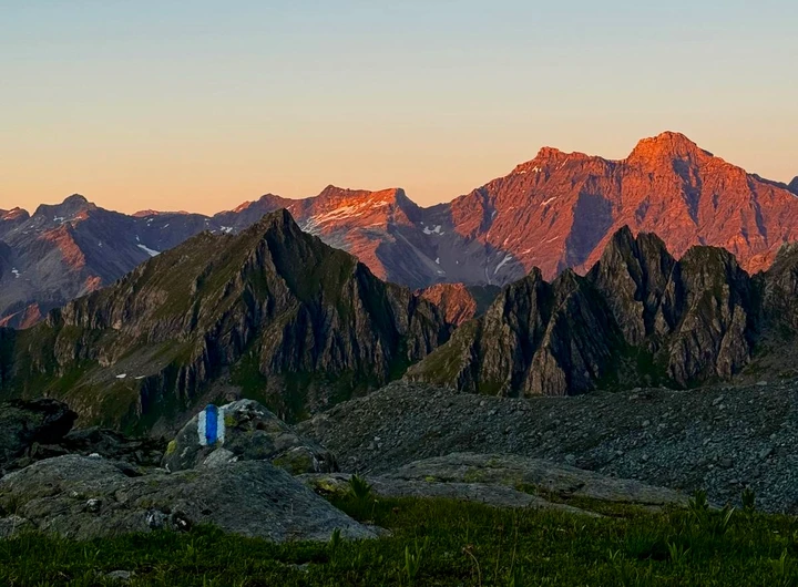 Sommets montagneux éclairés d’orange au-dessus de crêtes et de pentes dans l’ombre.